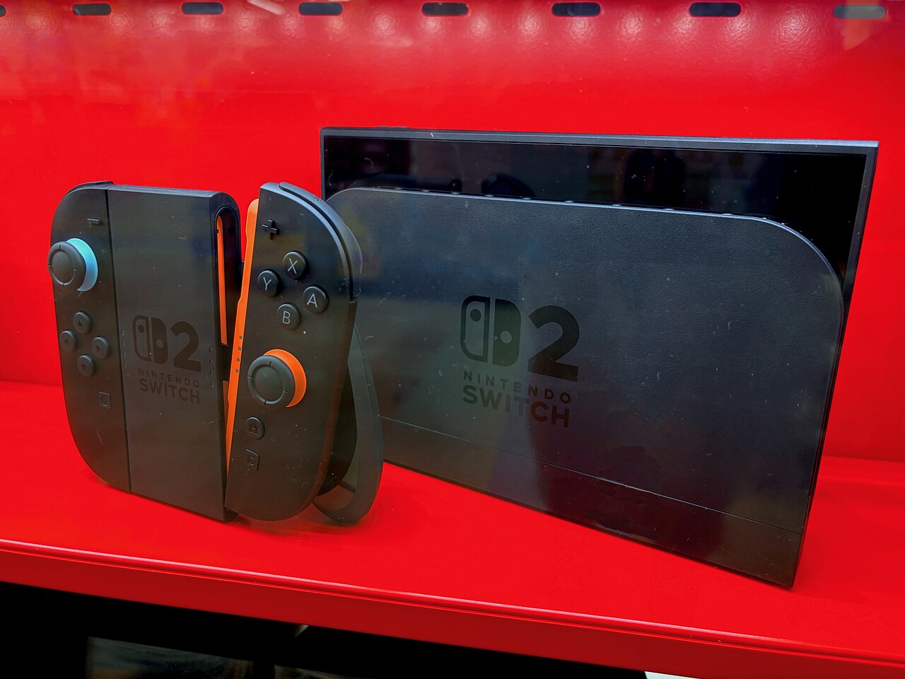 Nintendo Switch 2 dock, console and detached Joy-Con 2 controllers in a red display case