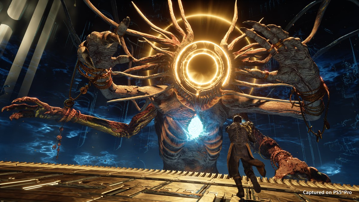 A Saros character faces a huge multi-armed creature with glowing golden rings, in an official screenshot captured on PS5 Pro.